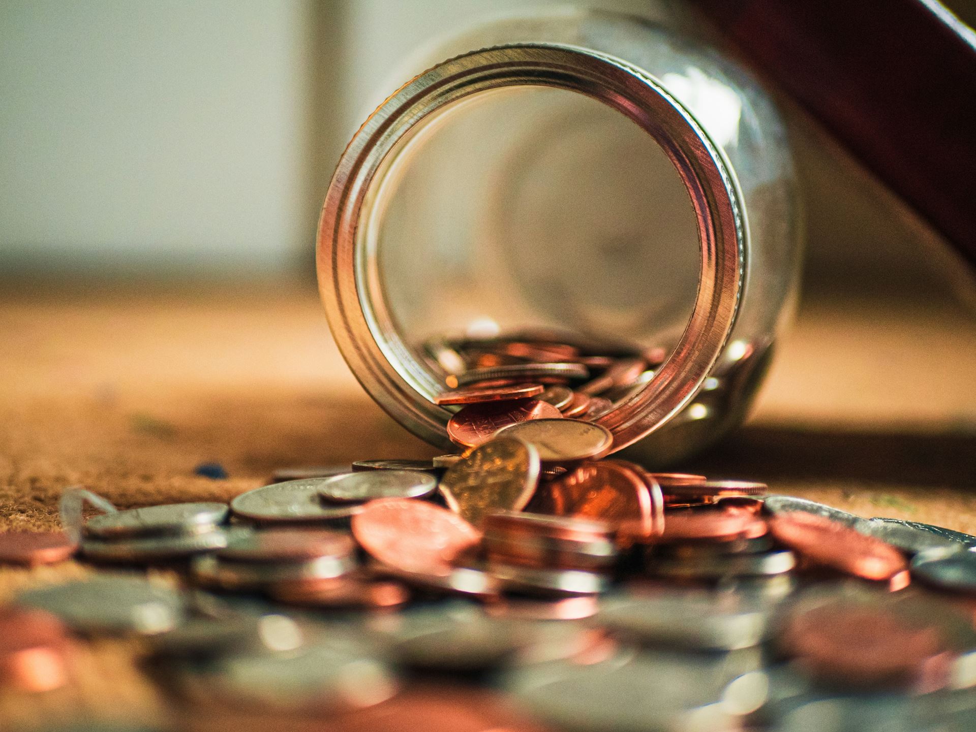 Coins falling out of a tipped over jar
